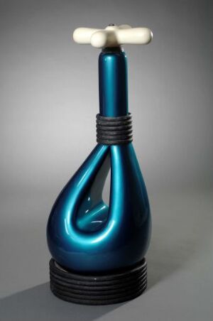  A lustrous, deep blue ceramic object by artist Jørgen Moe with a teardrop shape and a glossy finish features a spiral indentation, black banded neck, and a contrasting white cap with two parallel handles, set against a gray background. Artist and title unknown.