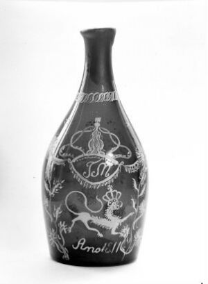  A black and white image of an elegantly shaped vase with a dark surface and light-colored, intricate etchings including a central emblem and decorative bands around the body and neck.