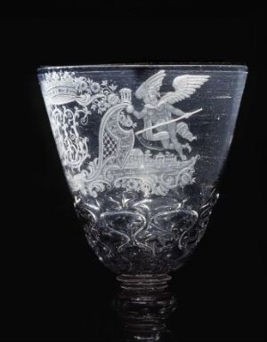  An intricately engraved glass goblet with a heraldic eagle emblem on a black background, showcasing fine details and craftsmanship in its design.