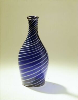  A tall, slender vase with spiraling blue stripes on a light background, featuring a glossy surface and a soft shadow cast to the right.