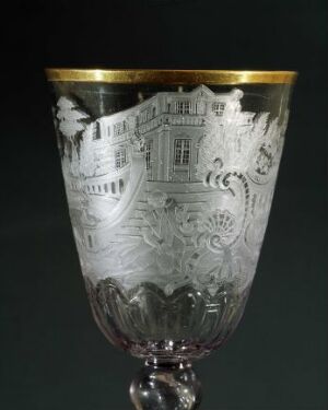  An exquisitely crafted glass goblet by Heinrich Gottlieb Köhler featuring detailed engravings depicting architectural designs, surrounded by ornamental foliage with a gilded rim atop a clear, short stem and flat base.