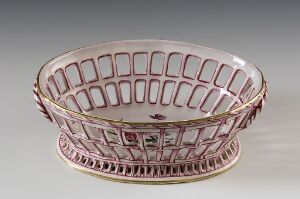 Alt-Text: An oval porcelain basket with a crisscross lattice design, highlighted by a gold and pink decorative band along the rim, set against a neutral background.