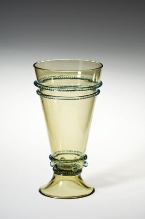  A pale yellow-green transparent glass goblet with two decorative dark bluish-green rings around the upper section and a patterned band around the midsection, set against an off-white background.