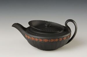  A black matte teapot with a rounded body and flat base, featuring a handle and a spout, with a band of round brown motifs encircling the center.