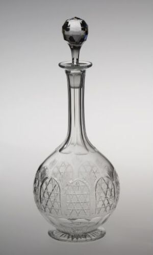  An intricately designed clear glass decanter with a spherical stopper, featuring detailed etchings of a stylized floral motif and sophisticated patterns, set against a graduated gray background.