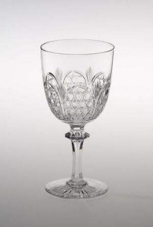  An elegant crystal wine glass from Hadeland Glassverk, with slip-cut floral and leaf patterns, reflecting light on a muted background, exuding luxury and fine craftsmanship.