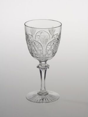  A meticulously etched crystal wine glass by Hadeland Glassverk, featuring a leaf and vine pattern on the bowl, a textured stem, and a stable base, set against a light gray background.