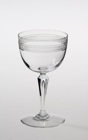  An elegantly crafted crystal wine glass by Hadeland Glassverk with intricate etchings on the bowl, a slender stem, and a flat base, set against a neutral background highlighting its translucent and reflective qualities.