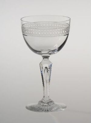  A Hadeland Glassverk crystal glass with etched patterns on the bowl and faceted stem, displayed against a light gray background, demonstrating fine Norwegian craftsmanship in tableware design.