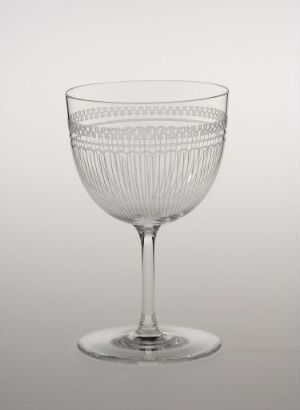  A clear stemmed glass with etched patterns on a light gray background.