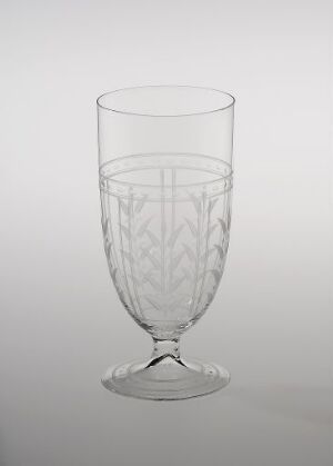  A clear glass with an etched vertical leaf or feather design stands against a light gray background, showcasing its decorative pattern and elegant structure.