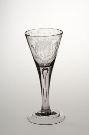  An elegant clear glass goblet with intricate designs on the bowl, standing against a light grey background.