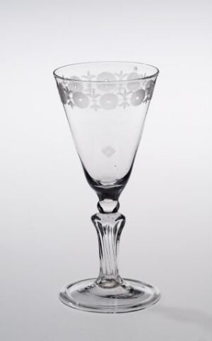  A clear glass goblet with a bell-shaped bowl featuring an etched floral pattern around the rim, set against a soft light gray background.