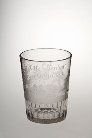  A transparent glass cup with elegant etched text and imagery against a gradient background that fades from white to light gray.