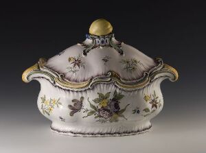  An antique white porcelain lidded dish with purple, green, and brown floral motifs, gold trim, and a gold finial on the lid, against a neutral gray background. Artistname and title are unknown.