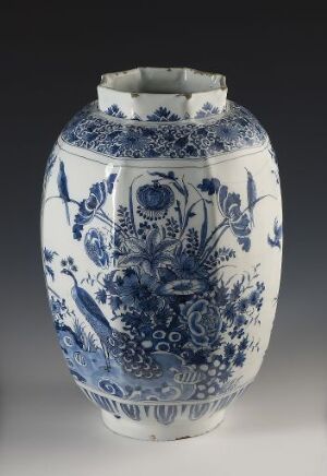  A traditional blue and white porcelain vase with scalloped rim and intricate floral and decorative designs on a gray background. The vase has a bulbous body and flared neck with varying shades of cobalt blue depicting detailed flowers, leaves, and ornamental patterns.