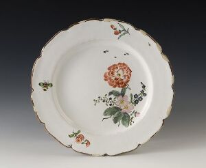  An antique ceramic plate with scalloped edges, featuring a hand-painted floral arrangement with a prominent orange and pink rose at the center, surrounded by smaller flowers and leaves in green, orange, and a hint of blue, with small insects painted near the rim. The plate has a glossy finish and exhibits fine craftsmanship.