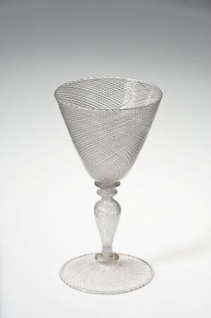 
 A delicate transparent glass goblet with a diamond point pattern on the bowl, a slender stem with a central knop, and a broad, flat foot, set against a light, neutral background.