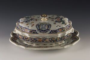  A rectangular porcelain serving dish with a cobalt blue and white design, accented with gold and touches of orange, green, and purple, featuring intricate florals and scrollwork, with a gold handle on the lid, set against a gradient gray background. Artist and title are unknown.