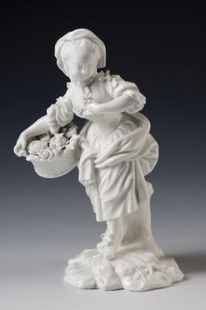  A white porcelain figurine titled "Våren," depicting a young woman in flowing robes holding a bouquet of flowers, embodies the essence of spring with a serene expression.
