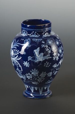  An ornate porcelain vase with a deep cobalt blue base and intricate white floral and fauna motifs, representing a high level of craftsmanship and traditional design.