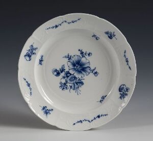  An antique blue and white porcelain plate with a central floral design and decorative border patterns, displayed against a grey background. Artist name and title are unknown.