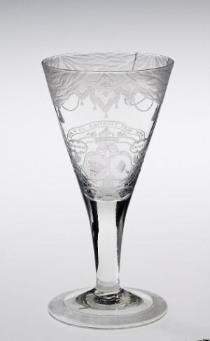  A clear crystal wine glass with floral etching on the upper half, set against a light gray or white background.