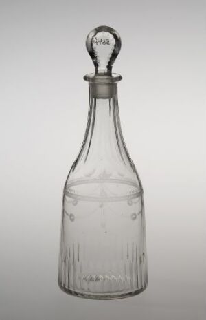  A clear glass bottle with vertical ridges on the lower body and a glass stopper with a circular handle against a light grey background.