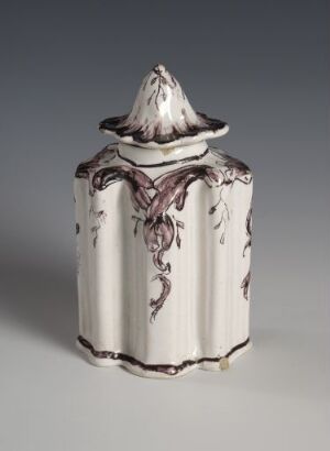  A cylindrical, white-glazed fajanse piece with a conical lid, hand-painted in manganese red with floral-like designs, reflecting traditional tableware artistry. The artist is unknown.