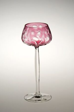  An elegant wine glass with a long, clear stem and a textured pink bowl featuring a darker pink swirling pattern, set against a gradient grey to white background.