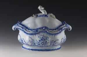  "Det rehnska mönsteret" - A faience covered dish with intricate blue patterns on a white base, featuring a wavy, scalloped design and a small white knob on the lid.