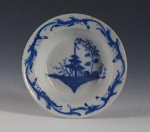  Antique-styled circular ceramic plate with intricate blue-and-white design featuring a central scene of a pavilion on an island with surrounding trees and a boat, encircled by a decorative floral border.