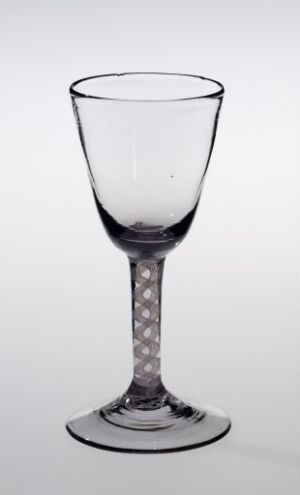  A clear, stemmed glass with a bell-shaped bowl and a decorative dotted stem stands against a light gray background.