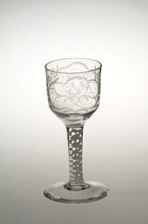  A clear, etched wine glass with a floral design and faceted stem on a gradient grey background.