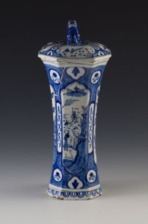  A tall, blue and white porcelain vase with a conical lid and intricate patterns including floral and lattice designs, suggesting a historical or cultural significance in its craftsmanship.