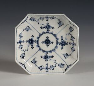  An octagonal white plate with intricate blue floral patterns, exhibiting a blend of sophistication and traditional porcelain design elements, with no visible artist's signature or title.