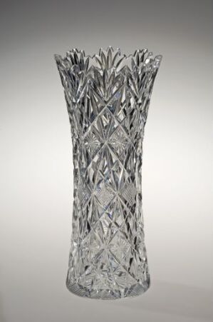  A clear crystal vase with an intricate pattern of etched facets, resting on a gray gradient background.