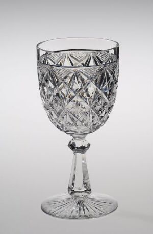  A clear crystal goblet by Hadeland Glassverk with intricate cut-glass patterns, positioned against a light gray background, designed for elegance and light reflection.