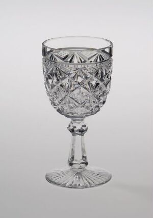  "Nordkapp" crystal goblet by Hadeland Glassverk, featuring intricate geometric cut patterns, with a slender stem and structured base, against a neutral gray background.