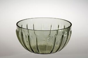  A shallow, transparent greenish glass bowl with subtle vertical ridges on its sides, displayed against a light background.