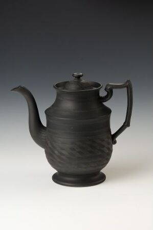  A black ceramic teapot with a textured surface, curved handle, and spout on a grey gradient background. Artistname and title are unknown.