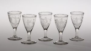  A set of five transparent engraved glass goblets by Hurdal glassverk, showcasing a clear material with floral motifs, arranged in a horizontal line against a soft grey background.