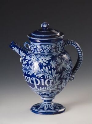  A ceramic coffee pot with a detailed cobalt blue and white floral pattern, featuring a rounded body on a pedestal base, a curved spout, and an ornate handle, set against a neutral background. Artistname and title are unknown.