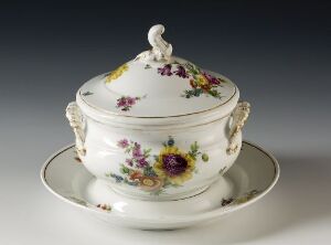  A vintage white porcelain soup tureen with hand-painted floral designs in shades of violet, pink, yellow, and blue, with green leaves, and scrolled handles, accompanied by a matching saucer.