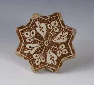  A star-shaped ceramic or stone ornament with dark brown color and intricate white or light beige floral patterns, reflecting a blend of aesthetic precision and artistry.