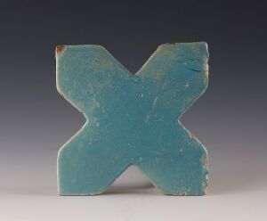  A standalone three-dimensional sculpture in the form of the letter "X," colored in a rich turquoise-blue with signs of aging and surface wear, displayed against a neutral gray background.