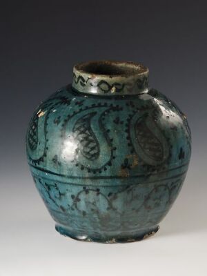  A small, spherical teal ceramic vase with dark inlaid paisley patterns and a brownish rim, set against a gradient background shifting from light grey to black.