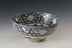  An intricately patterned blue and white ceramic bowl with a wide brim and floral decorations, showcasing East Asian design elements on a neutral background.