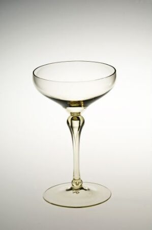  A clear glass champagne coupe with a gold rim, displayed against an off-white gradient background, highlighting its elegance and transparent quality.