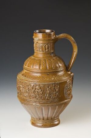  A stoneware jug titled "Susanna og de eldre" by Engel Kran, with a glossy salt glaze finish in warm brown tones, featuring a bulbous body with detailed relief decoration, a tapered ringed base, a cylindrical neck with a flared top, and a curved handle.